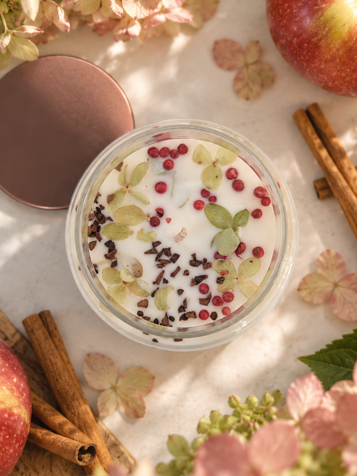 HARVEST apple spice soy candle in a glass apothecary jar with copper lid, styled with McIntosh apples and cinnamon sticks